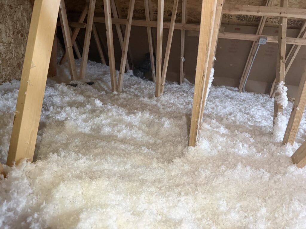 Attic with fresh blown fiberglass between the trusses