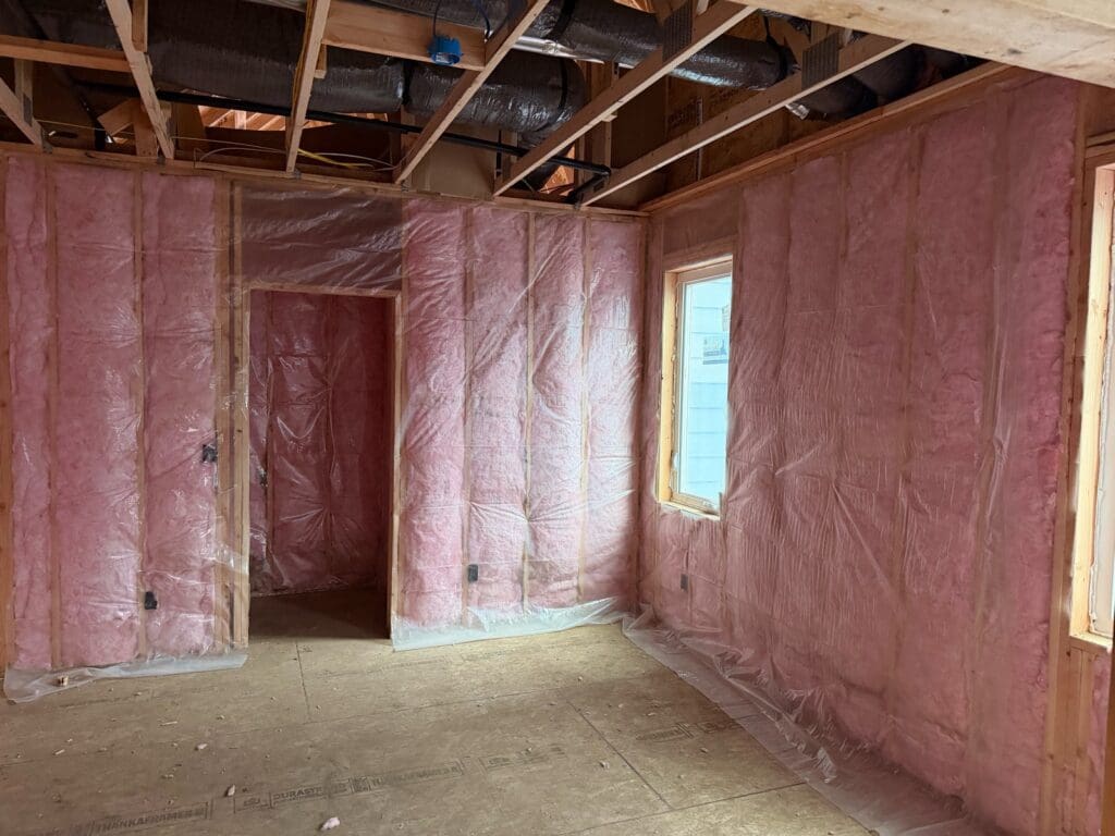 Fiberglass batts under a clear vapor barrier in new-build walls