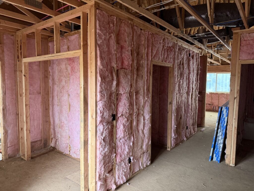 New-build interior walls filled with pink fiberglass batts