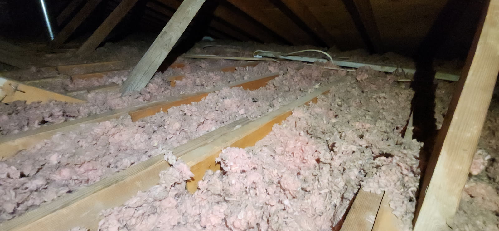 Attic before: old blown insulation clumped and settled between the joists, joist tops showing